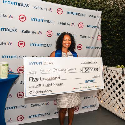 Intuit IDEAS 3.0 graduate posing with a ceremonial $5,000 grant check during the New Orleans graduation celebration.